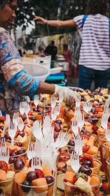 Woman selling cups of fresh fruit in Brick Lane, London. 