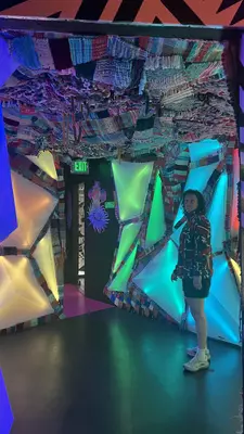 A person stands in a room with angled colored segments on the walls.