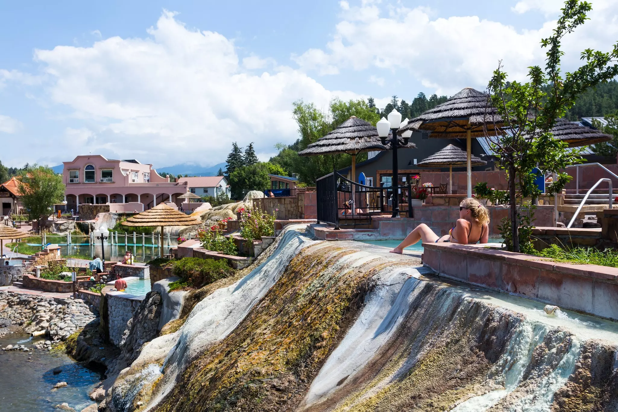A woman relaxes on a ledge at the edge of a pool in a spa