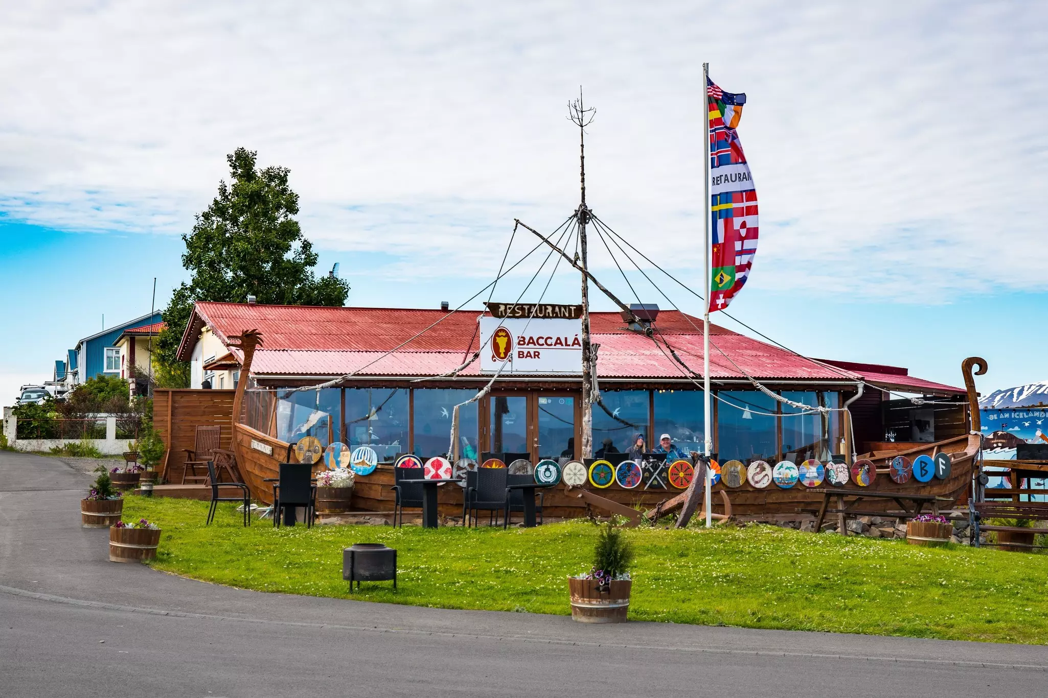 The exterior of a restaurant and bar styled as a ship decorated with flags and crests