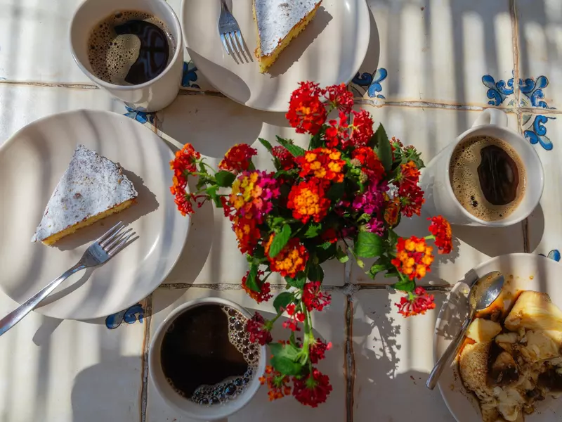 Table set for coffee and cake with a bouquet of flowers and almond cake
