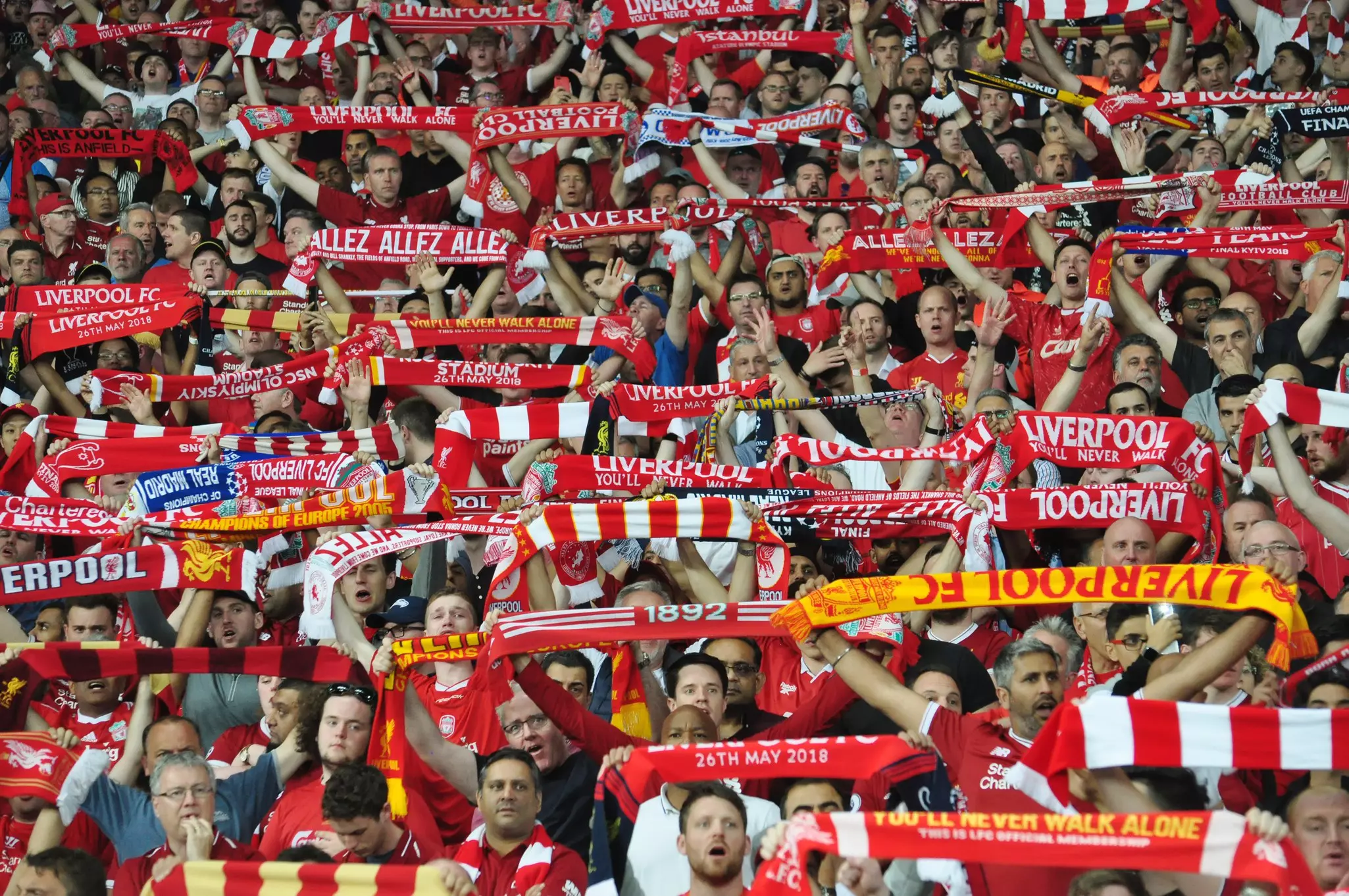 Liverpool football club fans waving scarves during a UEFA Champions League match.