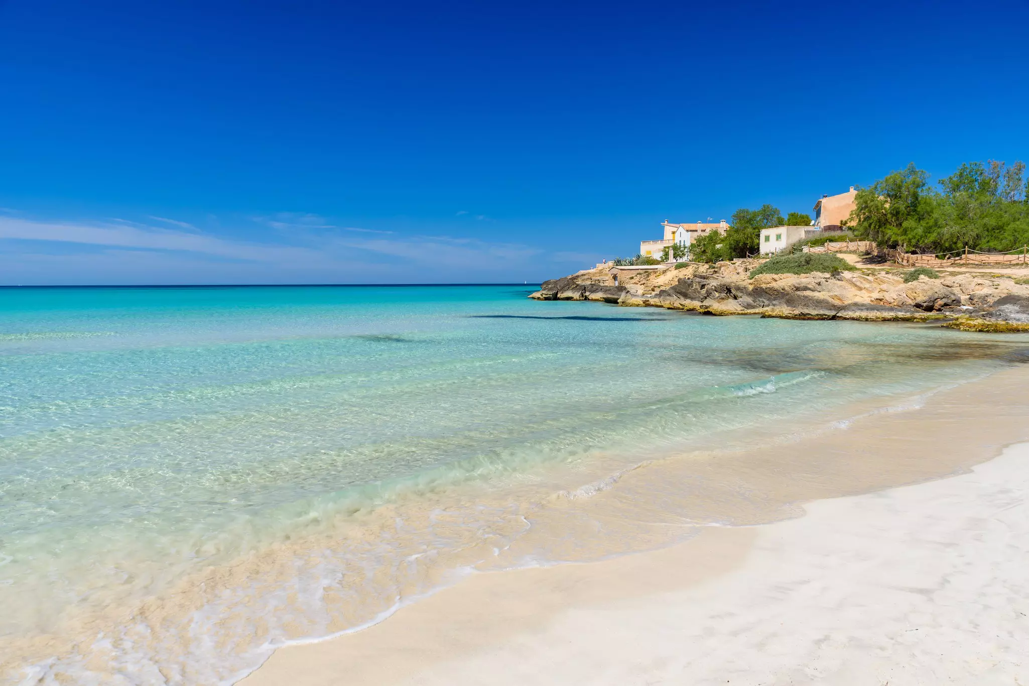 White sand beach with white washed houses overlooking it.