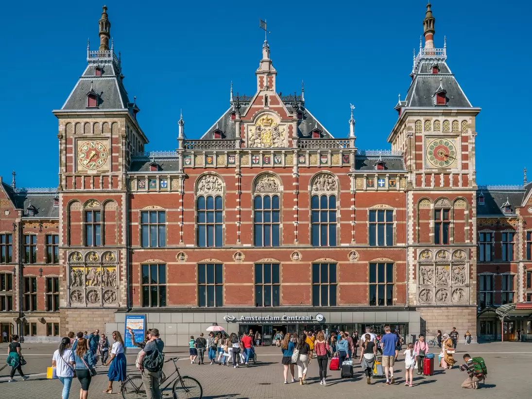 People walking towards the central train station of Amsterdam on a sunny day.