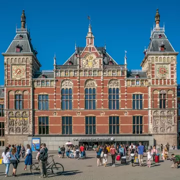 People walking towards the central train station of Amsterdam on a sunny day.