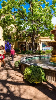 People walk past a fountain in a courtyard.