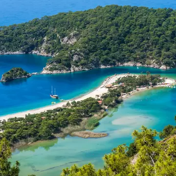 Beaches on a spit of land separating two coves of blue water.