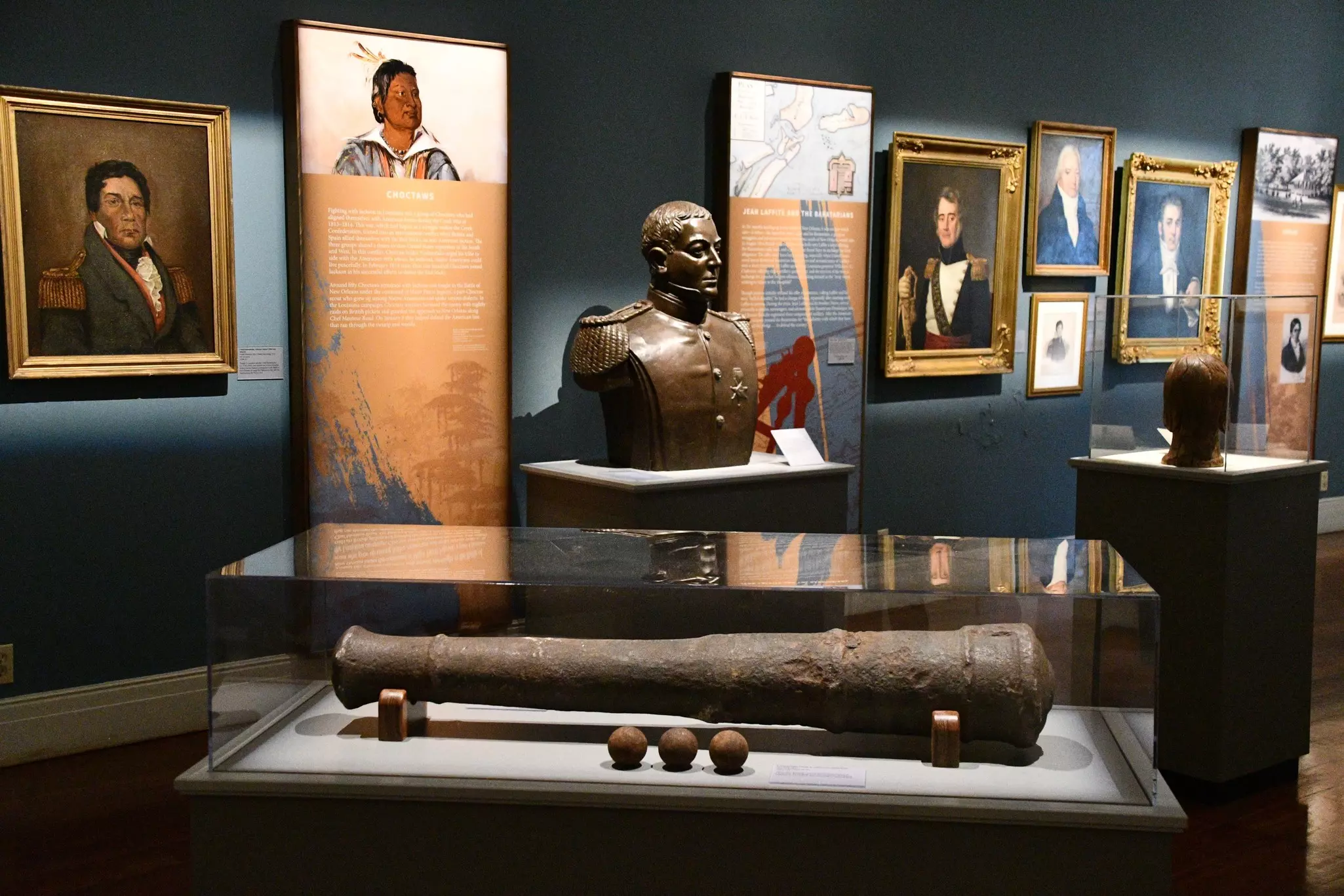 Paintings and artifacts are displayed in a gallery at a history museum.