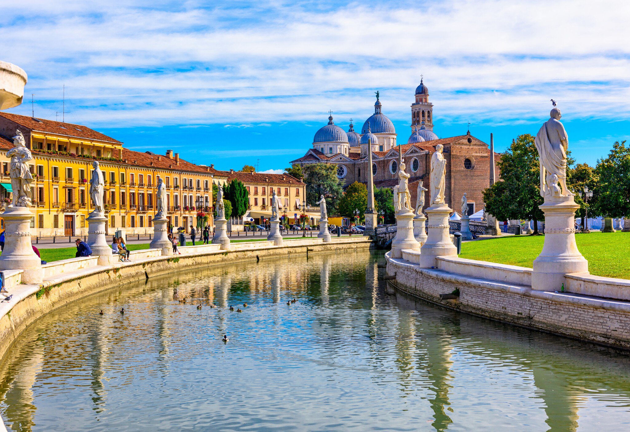 Statues line the canal at Prato della Valle square with the Basilica Santa Giustina (Abbey of Santa Giustina) in the background.