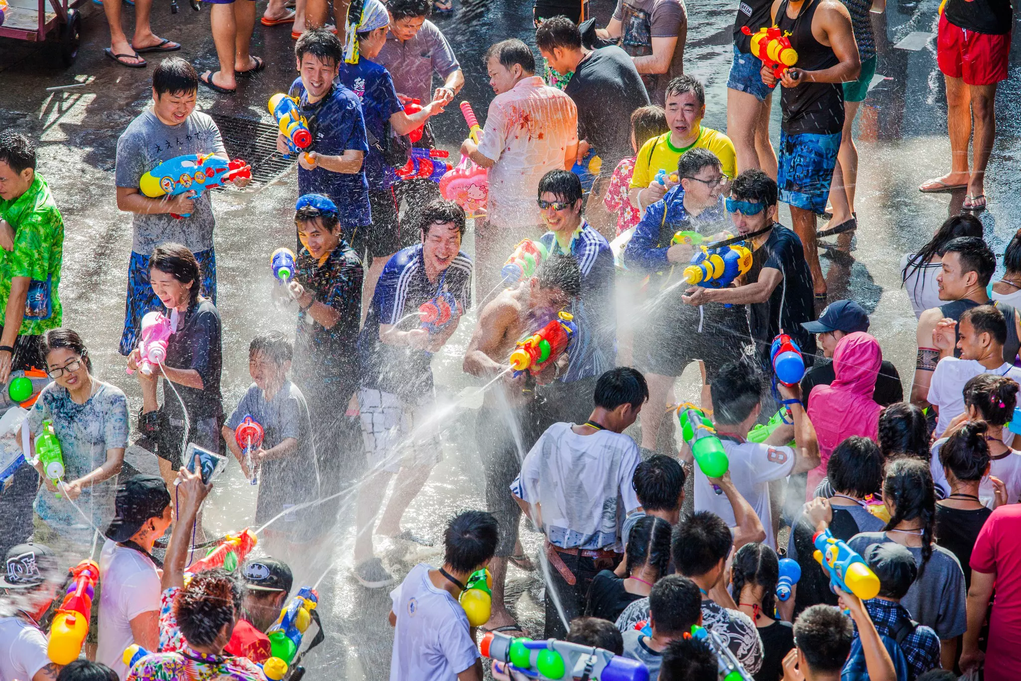 A huge water fight in the street with crowds of people soaking and being soaked.