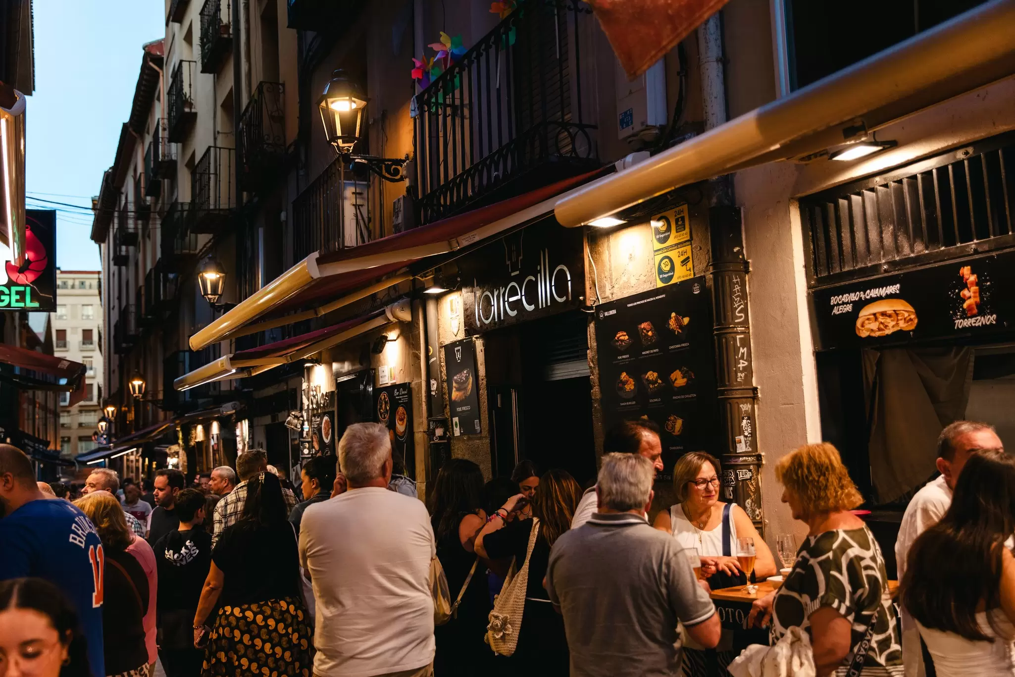 People eating and drinking outside a bar on a crowded street