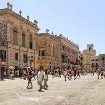 People walk across the Plaça des Born in the historic Ciutadella in Menorca, Spain.