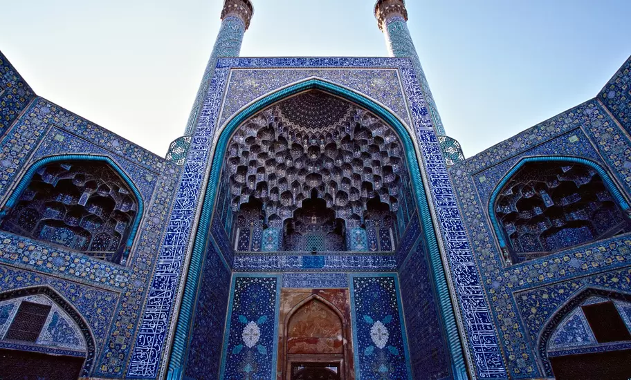 Blue-tiled entrance portal of Esfahan's Imam Mosque with honeycomb muqarnas vaulting and twin minarets