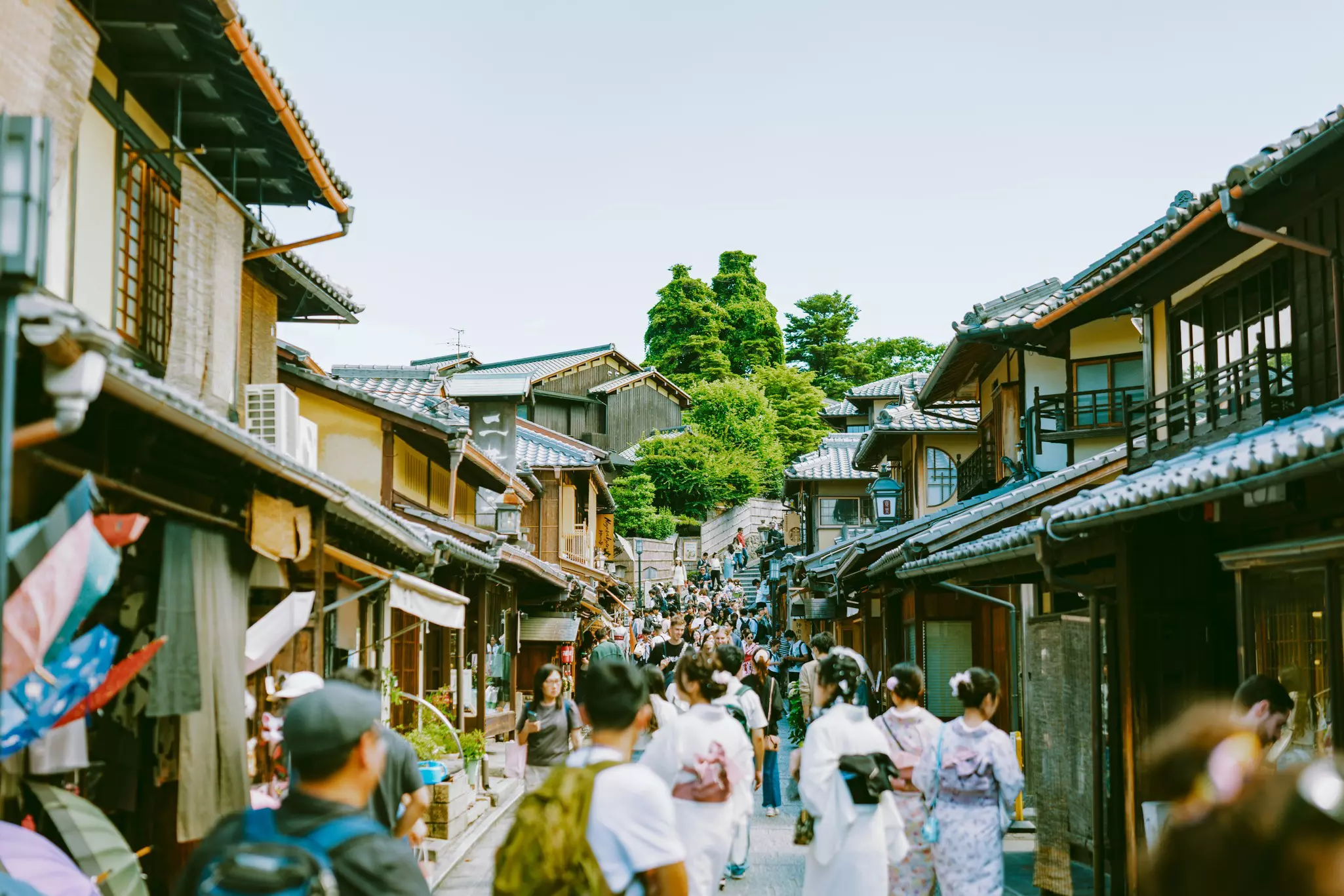 People exploring a pedestrianized street lined with Japanese-style wooden houses on a sunny spring day