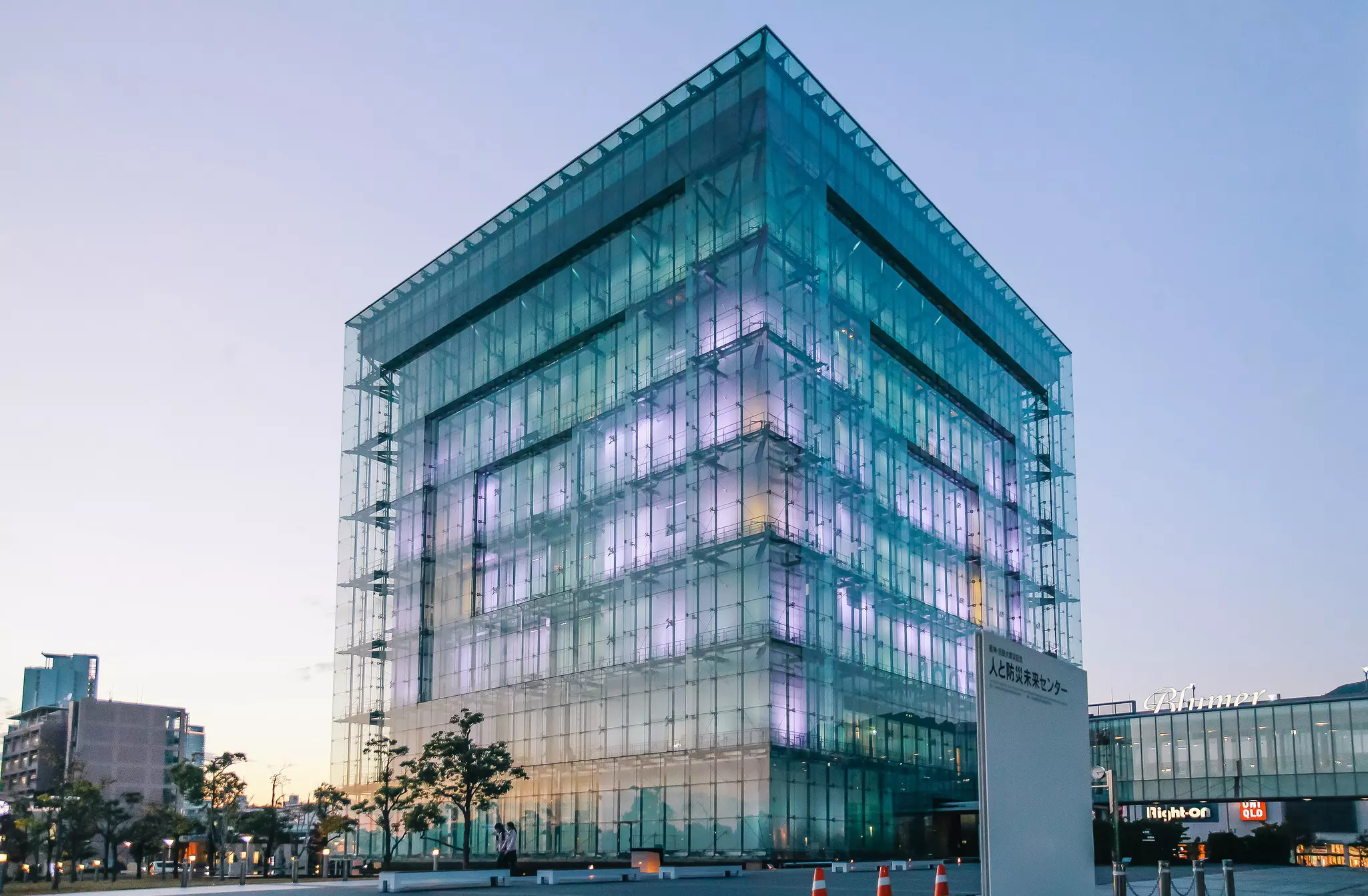 A large glass square building in Kobe glowing in the evening light