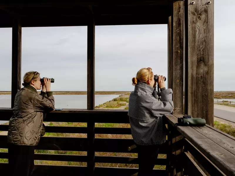 Two people in a tower look through binoculars.