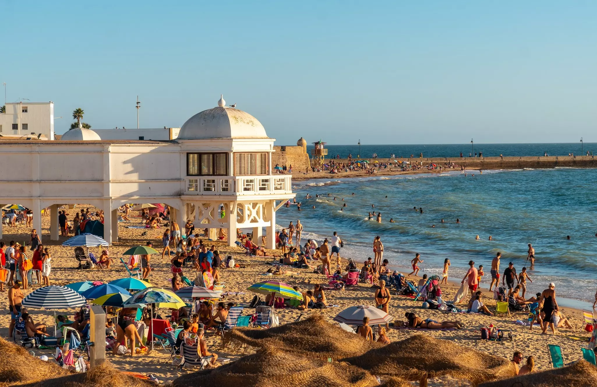 Bathers on Playa de la Caleta in the summer during sunset in the city of Cádiz, Spain.