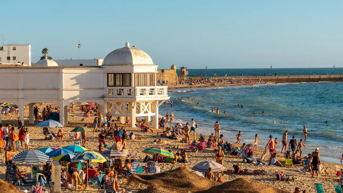 Bathers on Playa de la Caleta in the summer during sunset in the city of Cádiz, Spain.