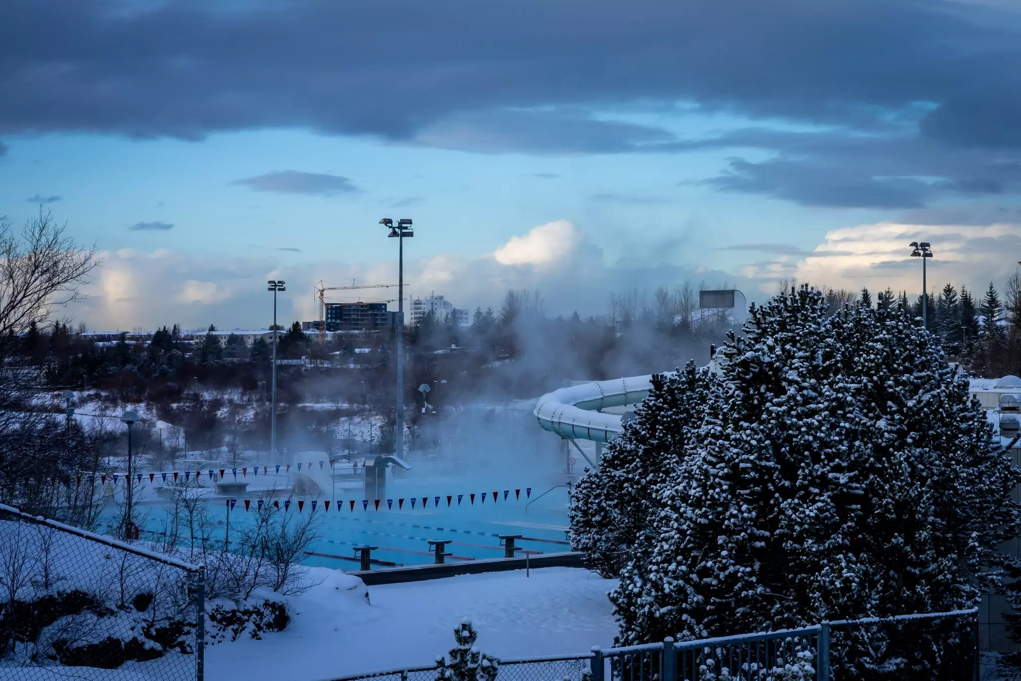 Steam rises from a heated outdoor pool, pictured in winter.