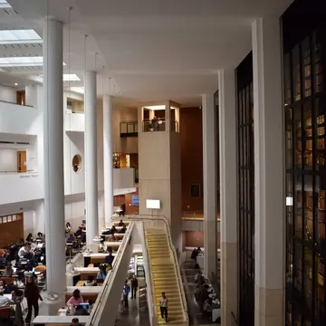 Aerial view inside the British Library, showing people studying around the atrium space next to the King’s Library—the famous glass-enclosed book tower, in London, UK.