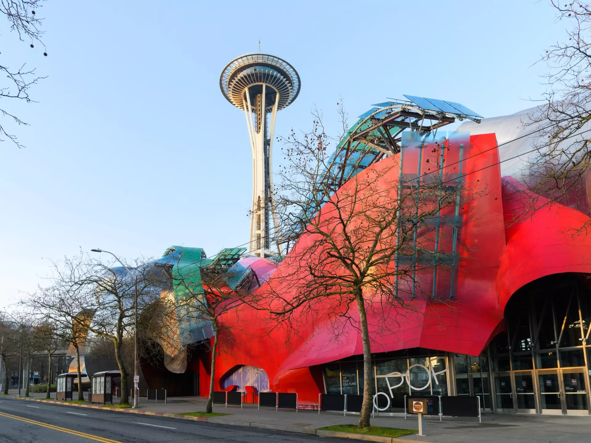 Modern building housing the Museum of Pop Culture or MoPOP in front of the Seattle Space Needle in morning light