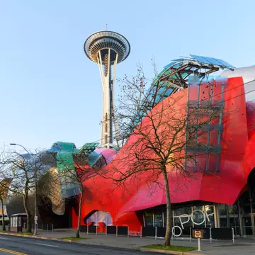 Modern building housing the Museum of Pop Culture or MoPOP in front of the Seattle Space Needle in morning light