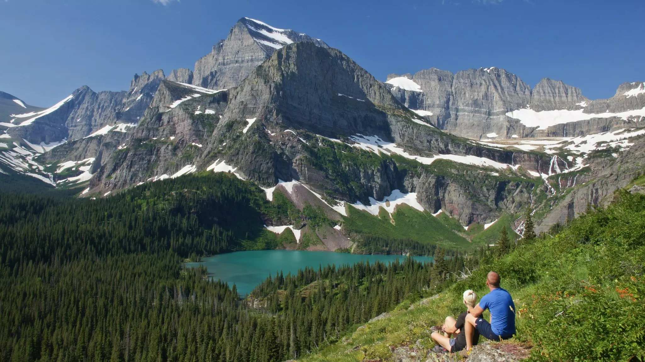 Hiking couple looking at Grinnell Lake, US Glacier National Park