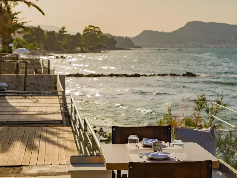 A set table at sunset at a restaurant overlooking the water.