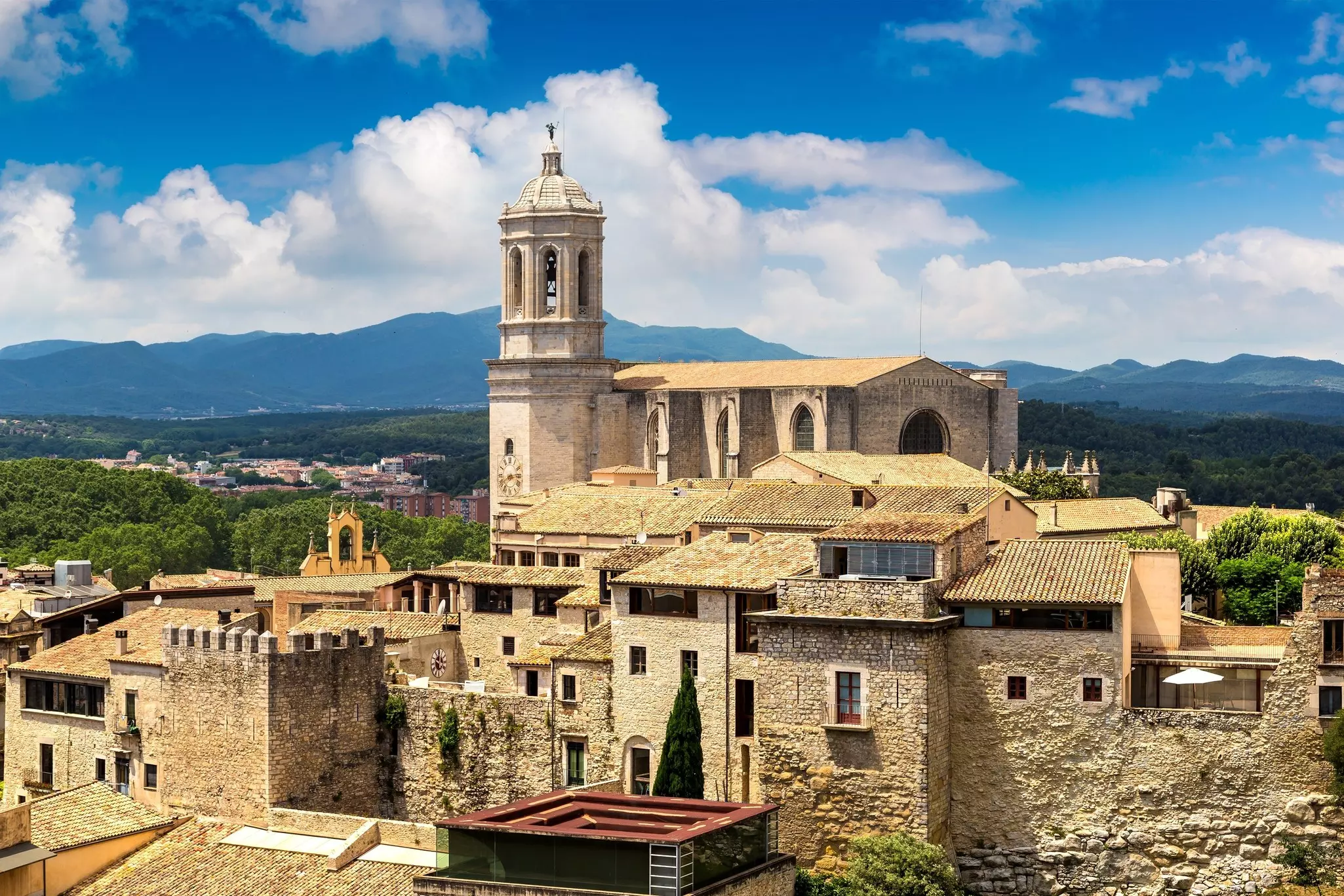 A city with a large central cathedral and buildings with terracotta rooftops.