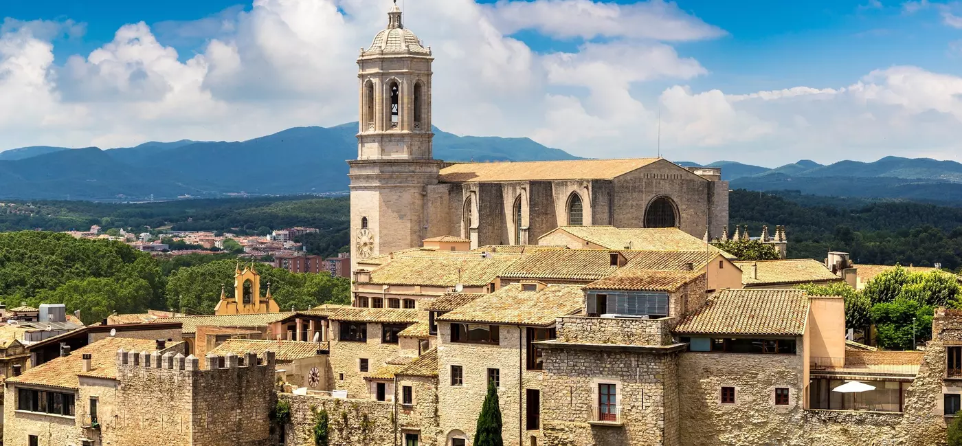 A city with a large central cathedral and buildings with terracotta rooftops.