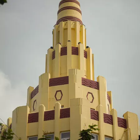The multilevel tower of a pale yellow building with maroon accents in India.