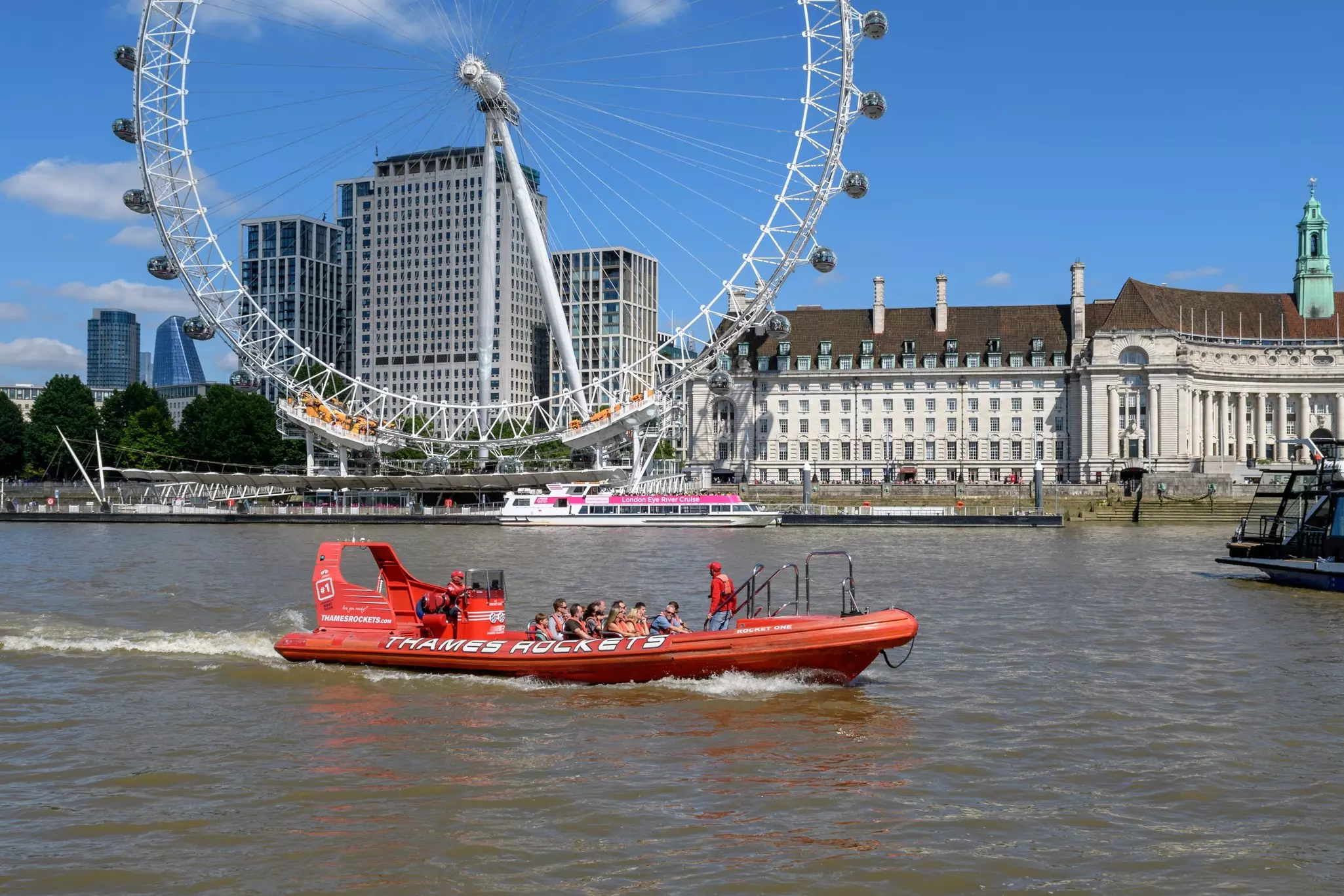London - July 7, 2022: An Thames Rocket boat carries passengers on the River Thames in front of the London Eye.