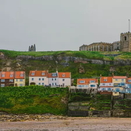 Pastel-colored houses line the waterfront with an ancient stone church on the hill above.