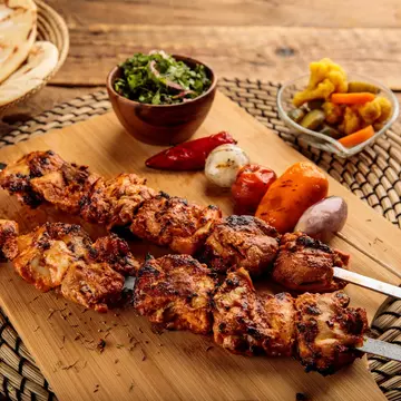 Shish Tawook kebab with pickle and bread served in a dish isolated on wooden background side view, License Type: media, Download Time: 2024-07-29T17:39:48.000Z, User: nic.dhoedt_lonelyplanet, Editorial: false, purchase_order: 56530, job: Global Publishing WIP, client: Lonely PlanetMiddle East 10, other: Nicolas D'Hoedt