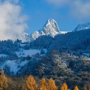 A high snow-covered mountain peak rises above forested slopes: Col de Jaman in Montreux, Switzerland. 