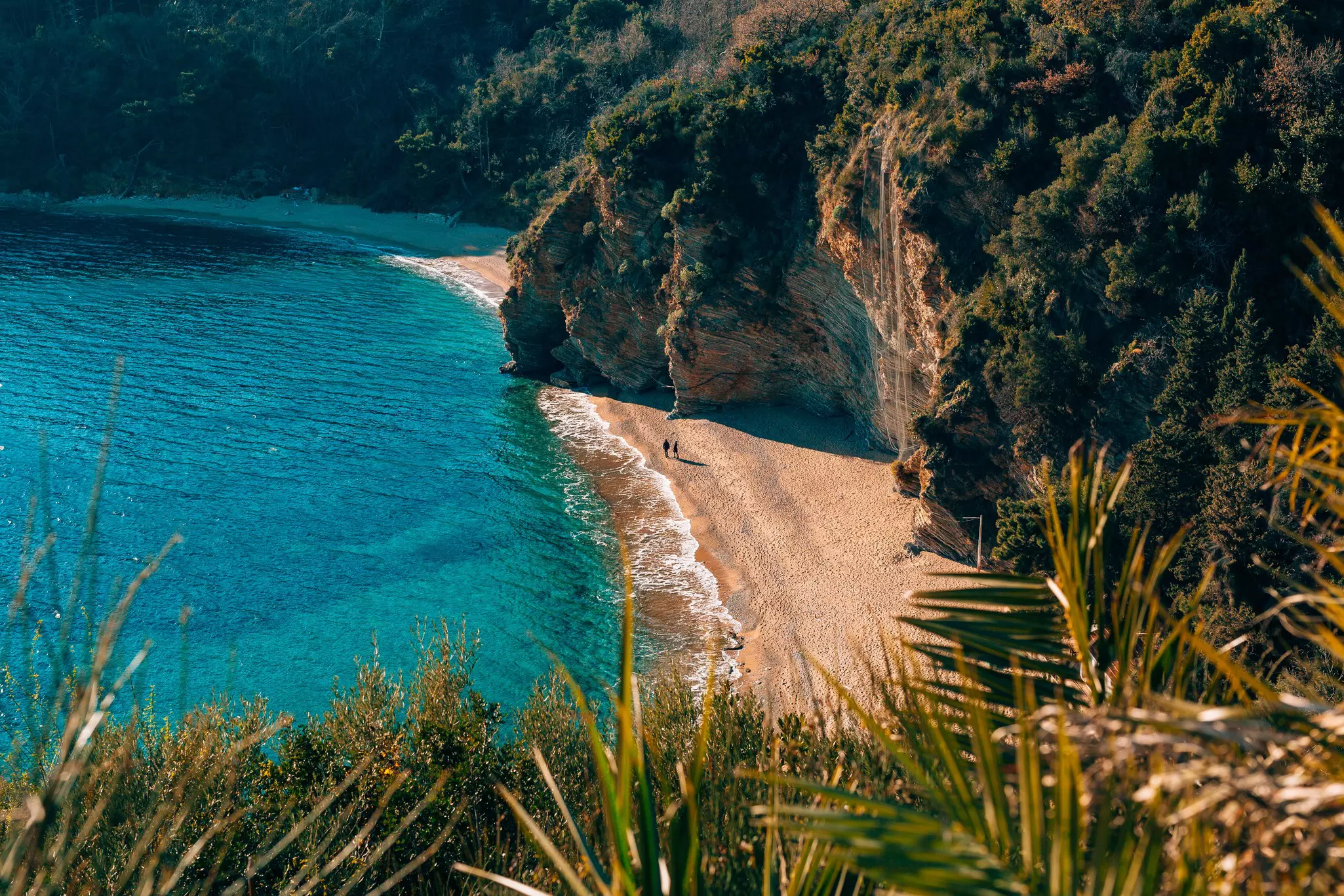 A wide shot of two beach bays in a cove, surrounded by cliffs.