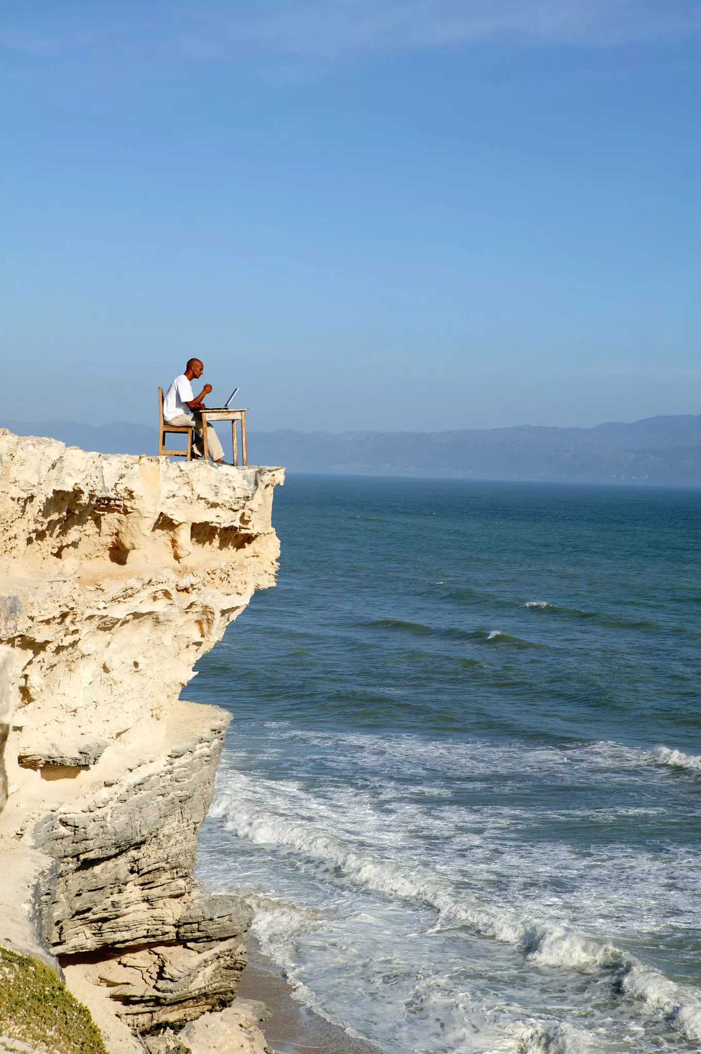 A young bearded man working on a laptop on top of an ancient fortress in Jaisalmer.