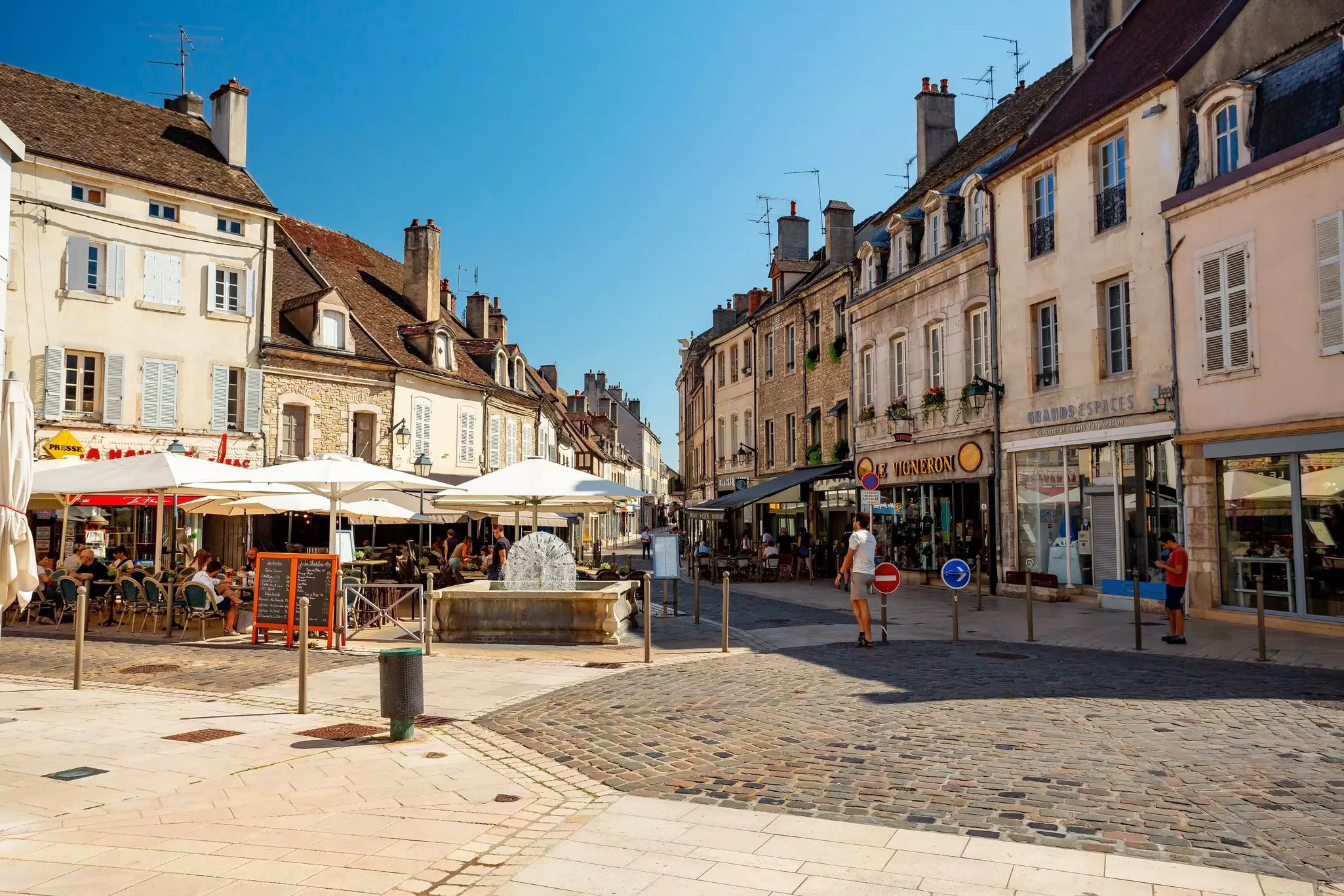 An old-town square with tables and chairs outside restaurant terraces.