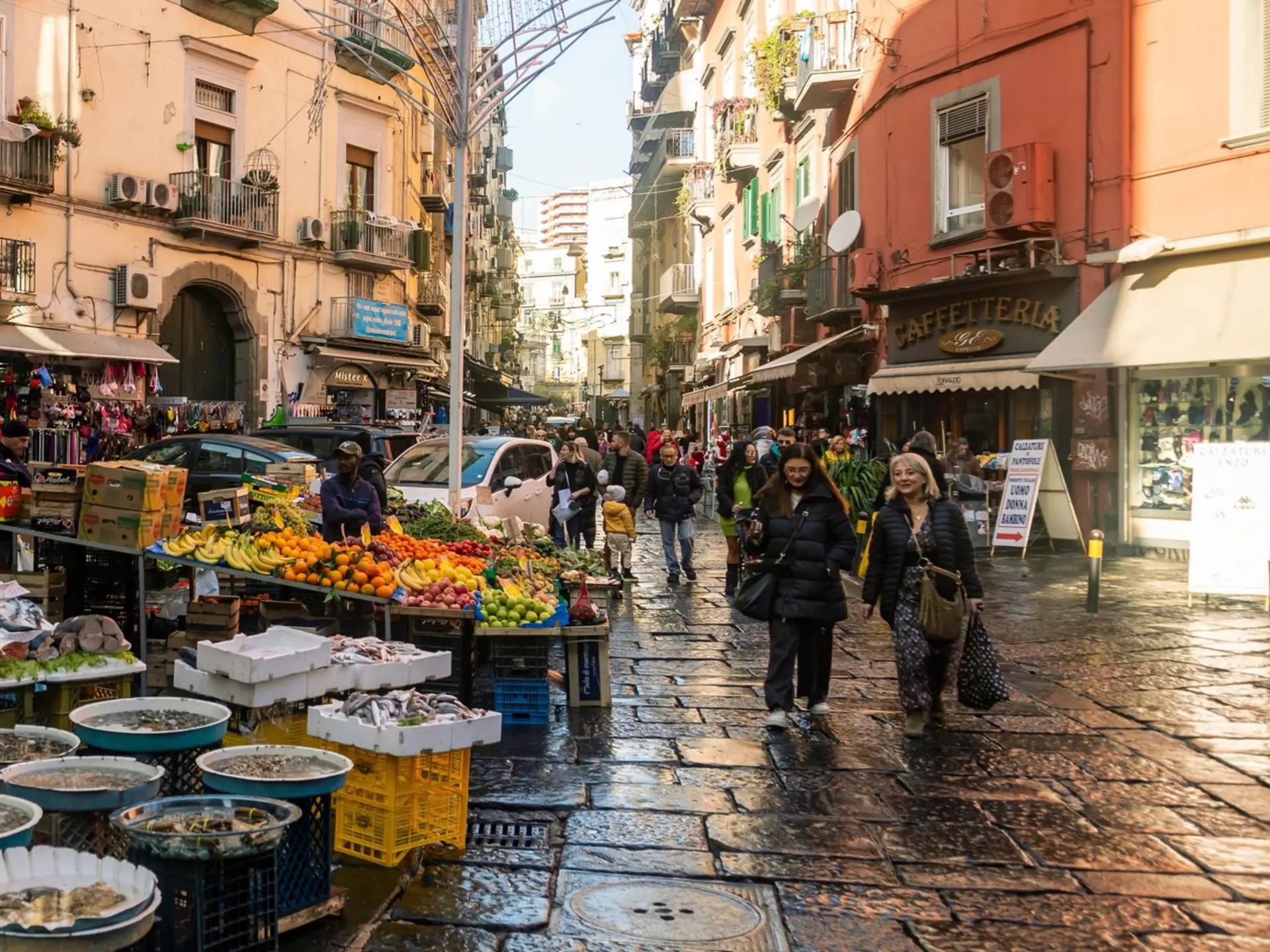 A seafood stand at a street market on a cobbled street in a city.