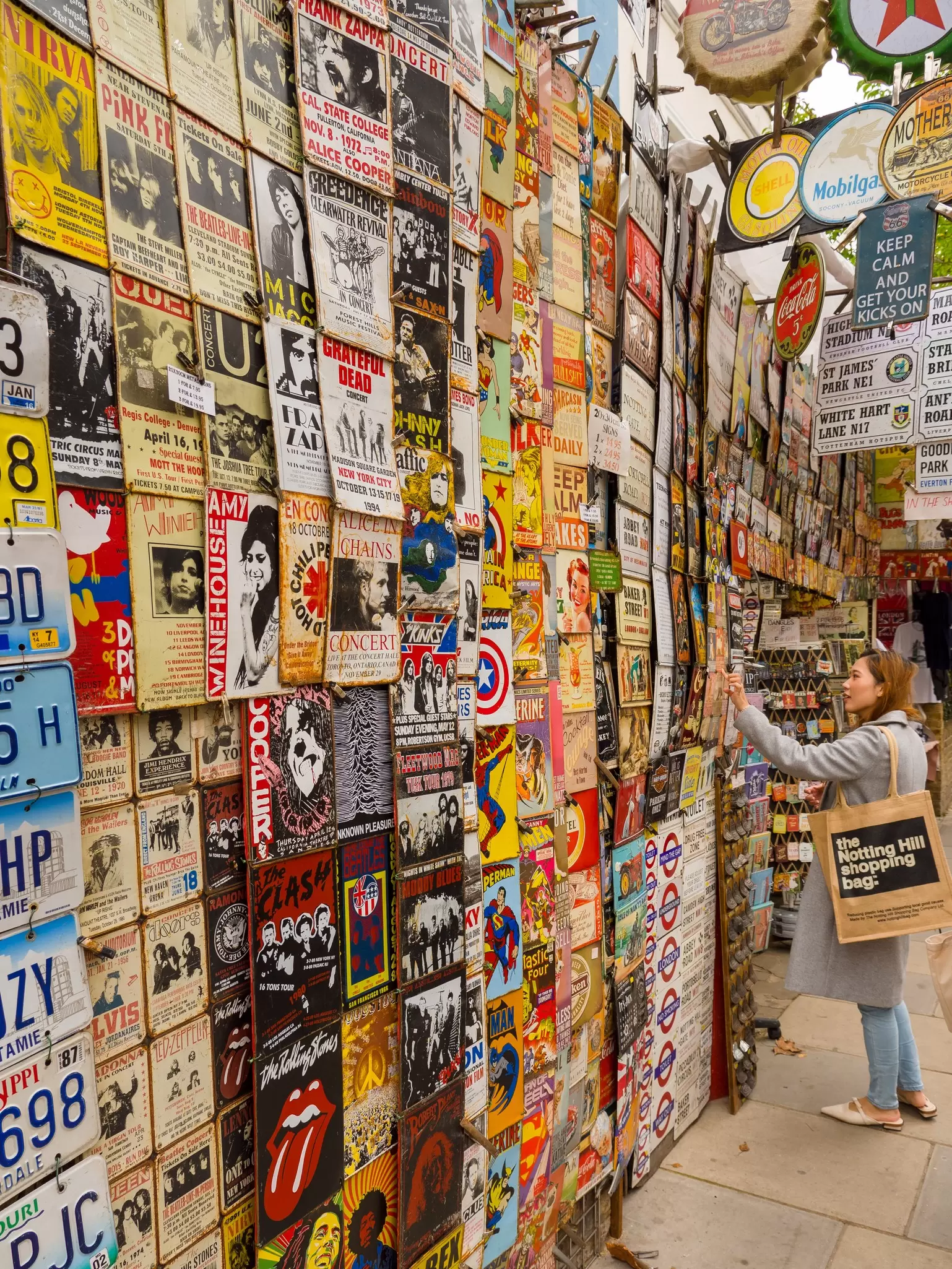 A shopper looking at retro signs at a shop on Portobello Road in London, UK.