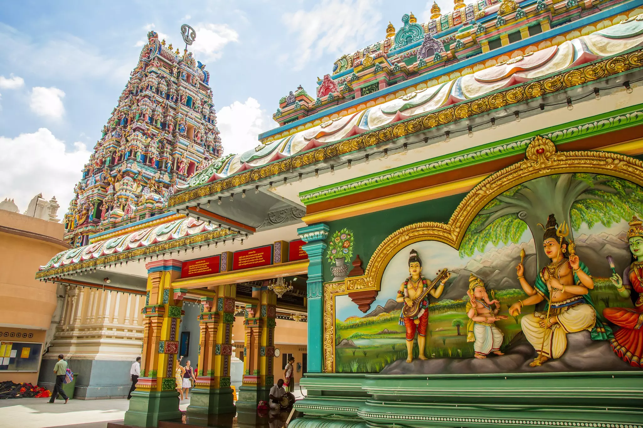 An intricately decorated and colorful Hindu temple with decorations all over its square tower.