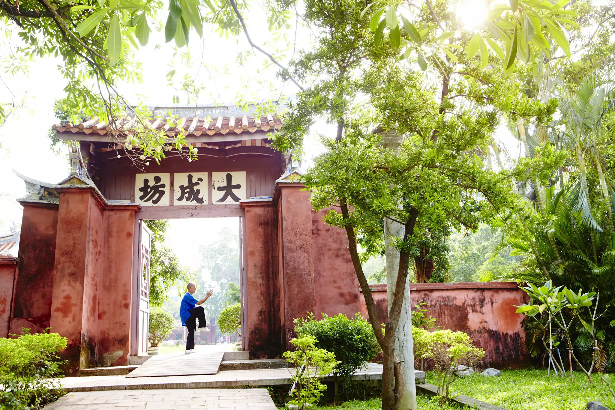 A man doing tai chi in a doorway to a temple