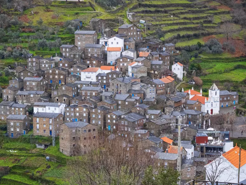A village of gray stone buildings in a green hillside.