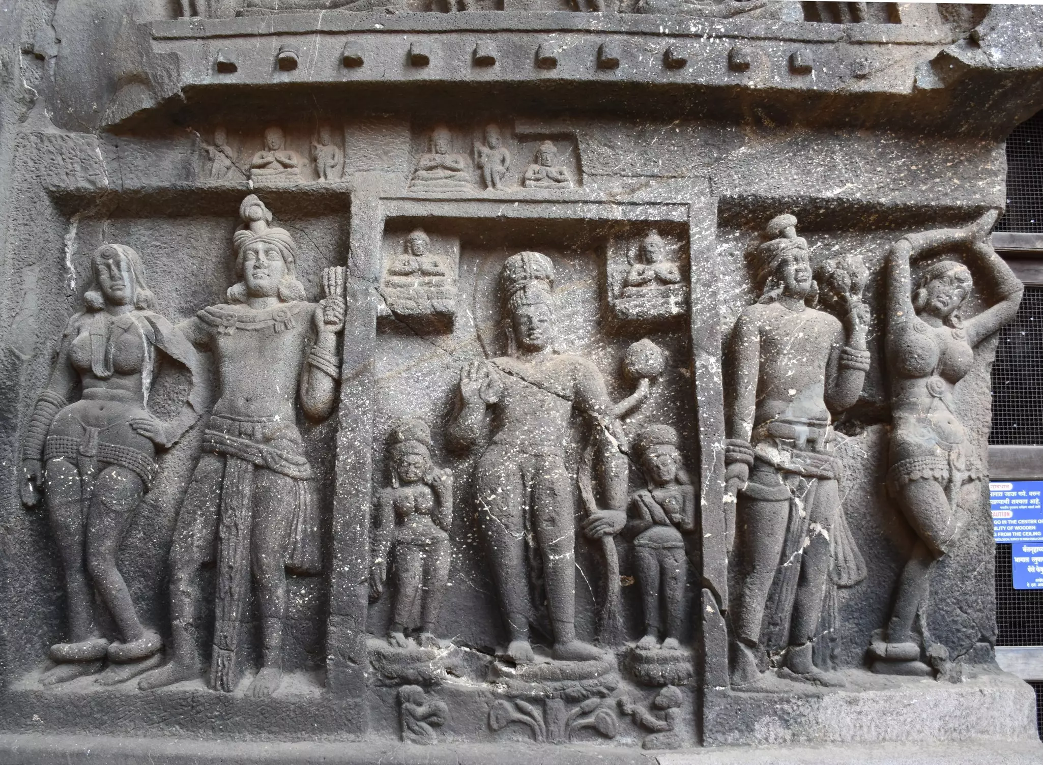 Female figures are carved in relief on a stone sculpture panel.