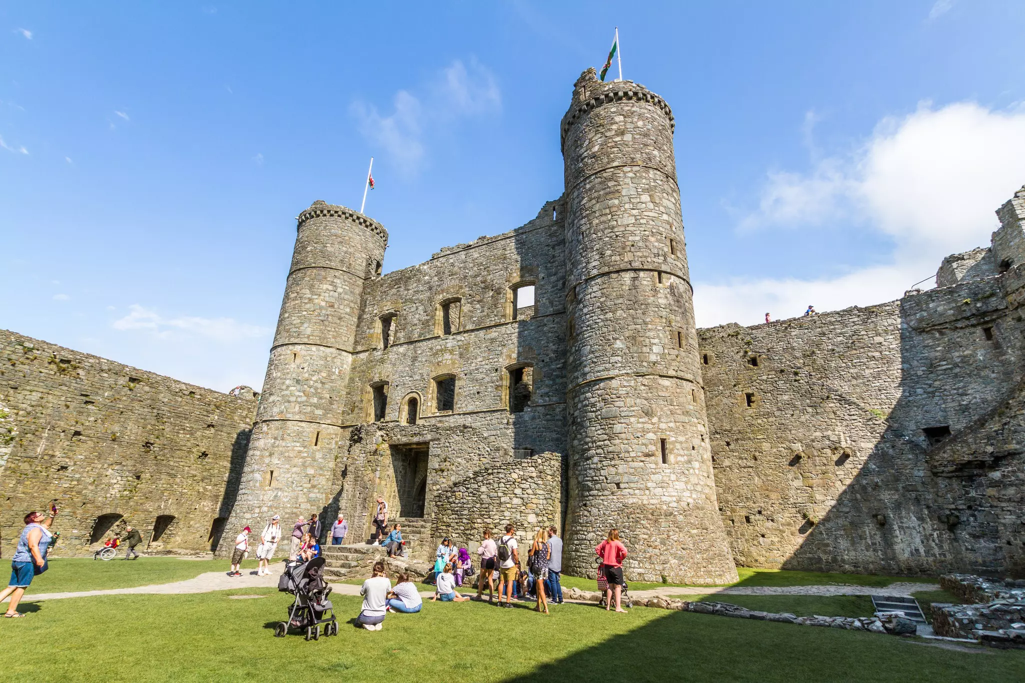 Visitors admiring the towering walls of Harlech Castle, Wales.