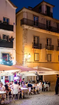 A neighborhood at dusk with people dining outside restaurants