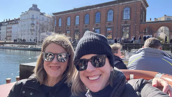 Close-up of two women in sunglasses smiling on a canal boat.
