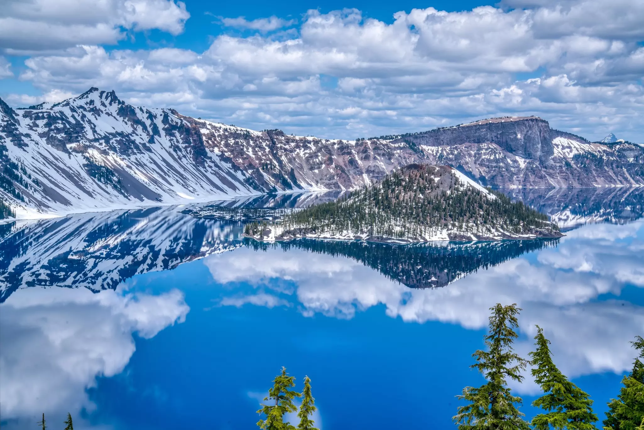 Snowy mountains reflected in a lake in a vast caldera.