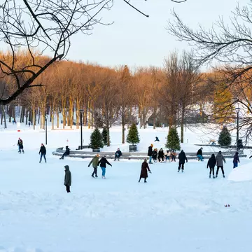 Montreal Quebec Canada January 22 2020: Skaters at Pavillon du Lac aux Castors on mount Royal park with trees in background, License Type: media, Download Time: 2025-12-09T18:04:51.000Z, User: lonelyplanetmedia, Editorial: true, purchase_order: 65020 - Marketing or Sales - this includes sponsored articles, job: Montreal , client: Montreal , other: Pia Peterson Haggarty
