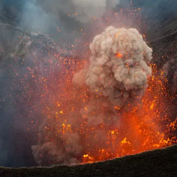 A huge plume of smoke - surrounded by an explosion of magma - makes its way out of Mt Yasur's crater.